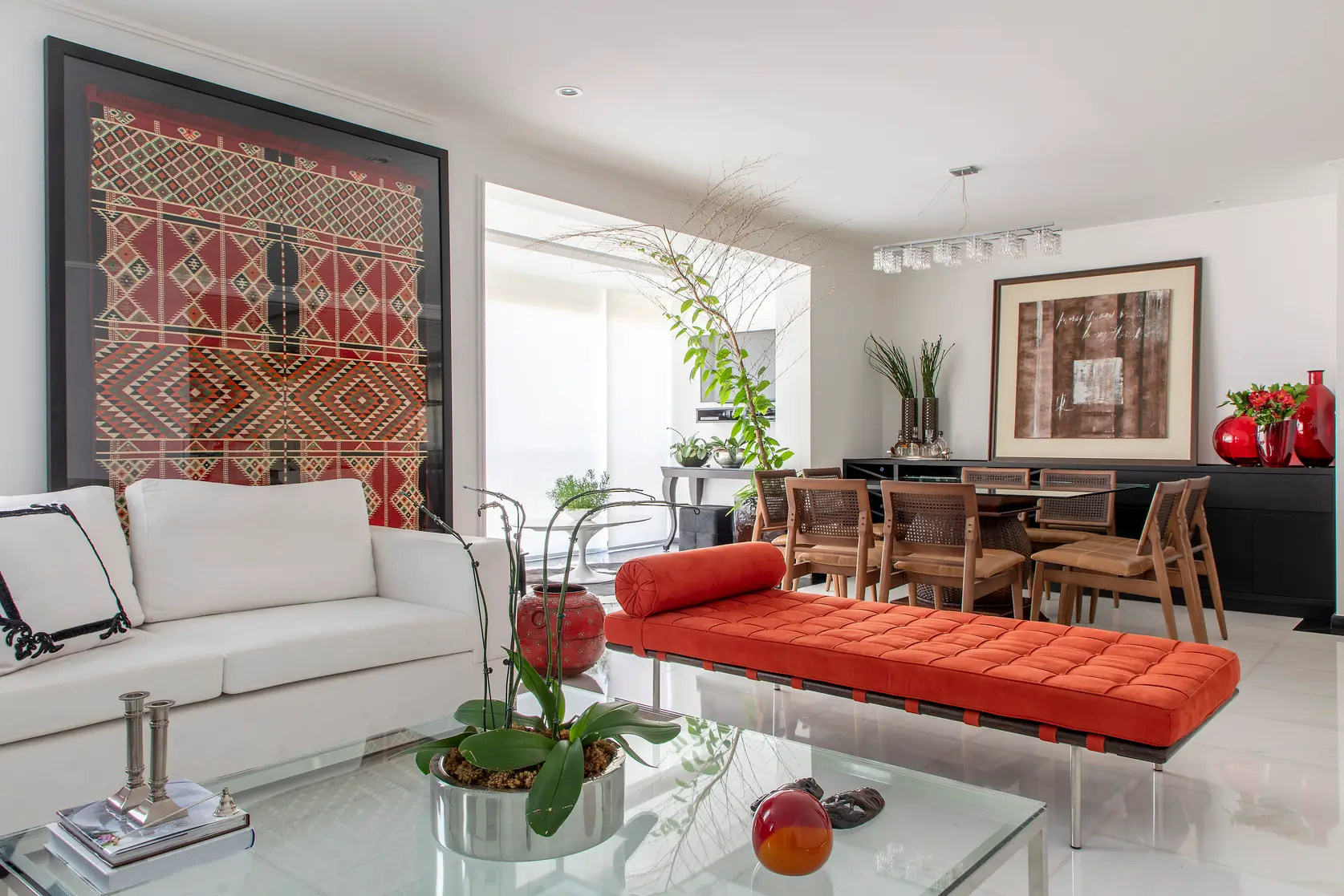 Sala de estar integrada com sofá branco, daybed laranja e kilim emoldurado em obra gerenciada pela MIS Arquitetura