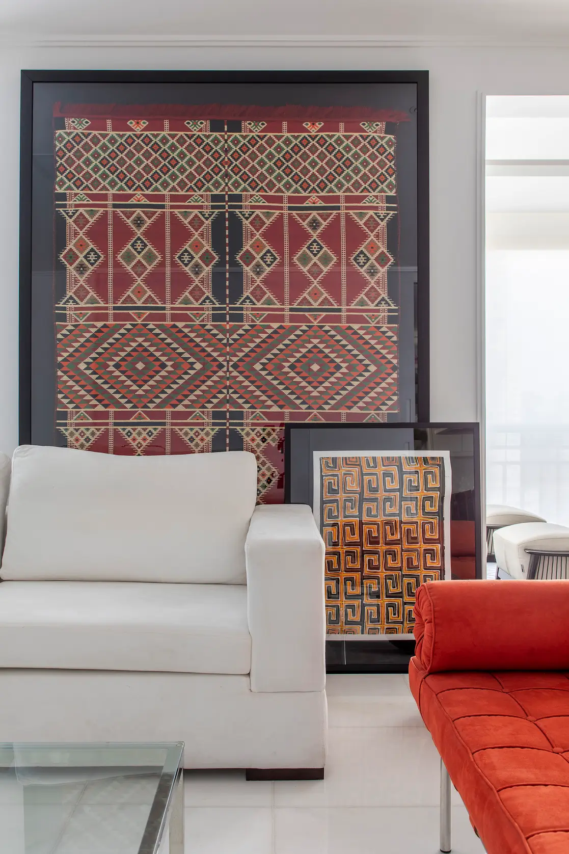 Kilim emoldurado e quadro de tecido africano atrás do sofá branco em apartamento projetado pela MIS Arquitetura